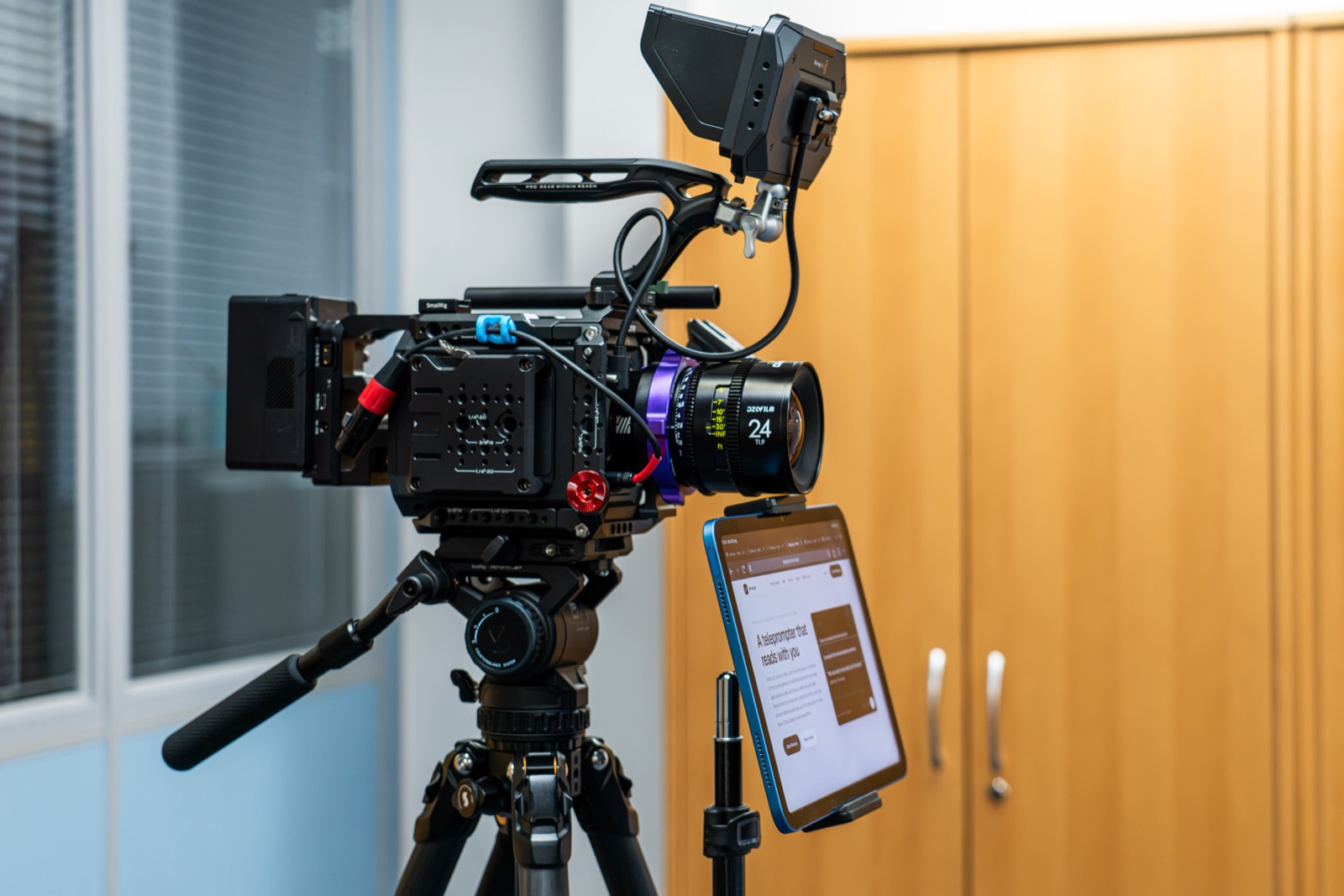 A tablet on a stand parked directly beside a cinema camera lens, showing the script where the presenter is looking.