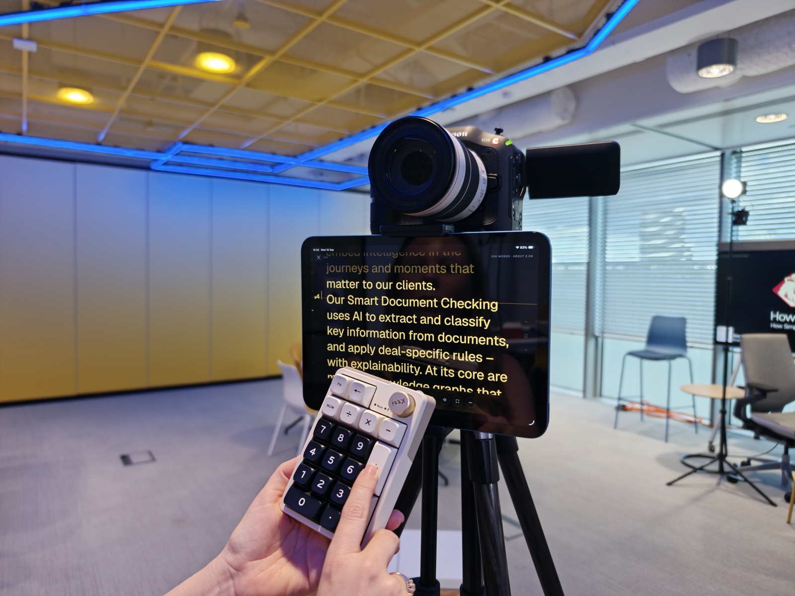 A Bluetooth numpad in hand, working the prompter on a tripod from off camera